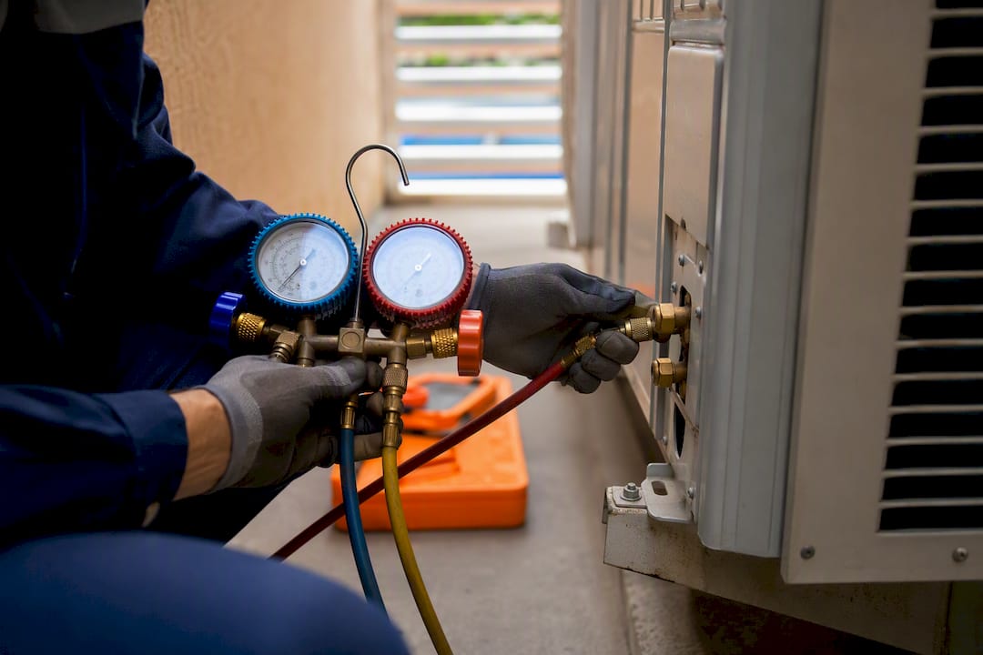 Technician connecting gauges for refrigerant service