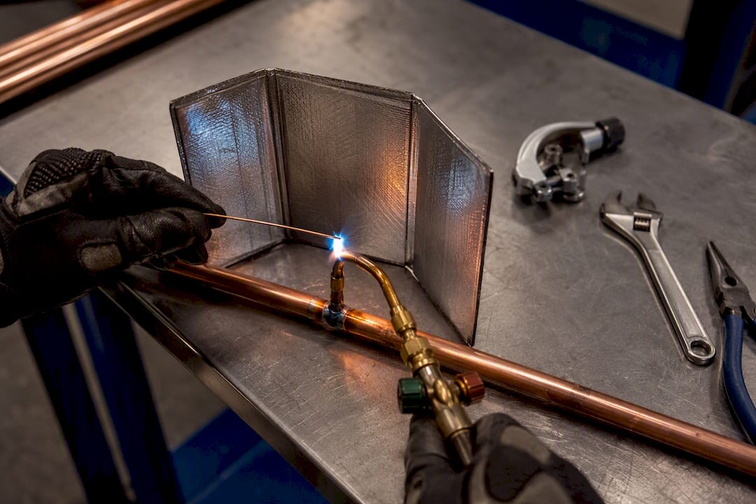 Technician brazing a copper refrigerant line