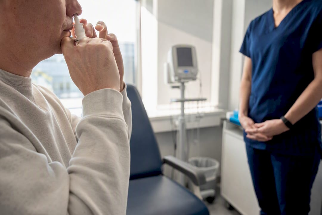 Patient self-administering nasal spray in dosing room