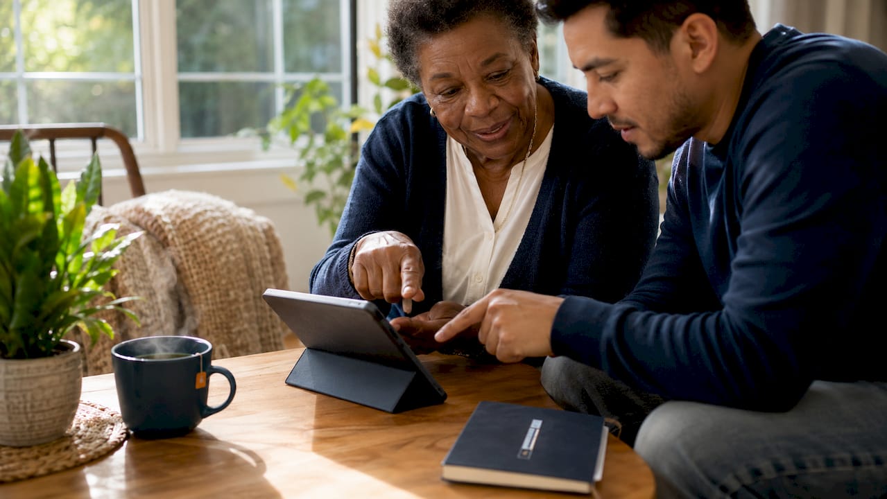 Hands of caregivers coordinating telehealth on tablet