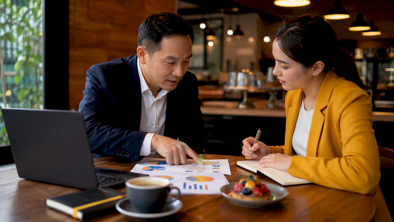 Hands pointing at newsletter ad budget charts