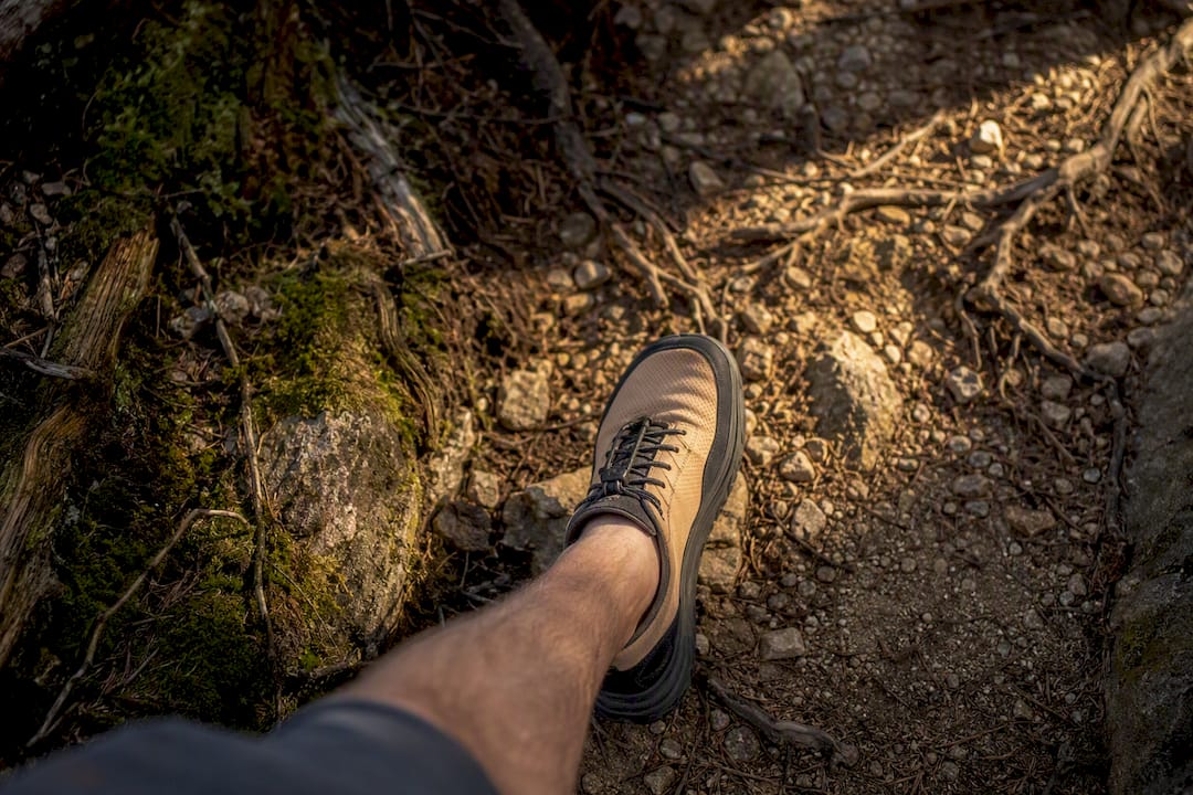 Fuß in Barfußschuh auf felsigem Pfad, Sohlenstärke sichtbar