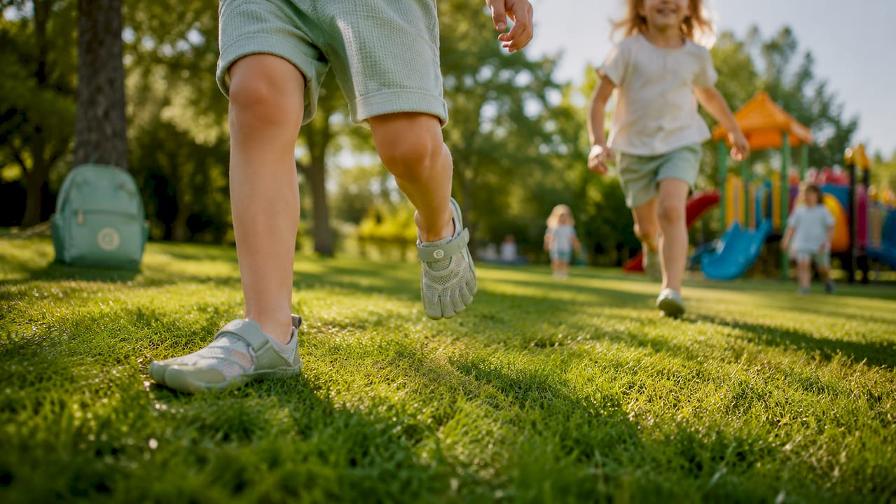 Kinder, die mit ihren kleinen Füßen in bequemen Barfußschuhen über einen warmen Holzboden laufen.
