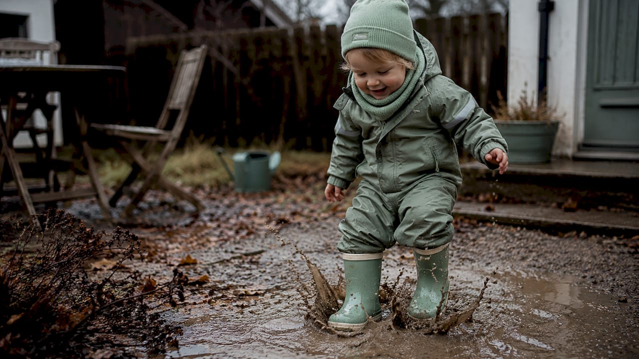 Kinderstiefel, die fröhlich durch Matsch und Pfützen stapfen – ganz nah eingefangen.