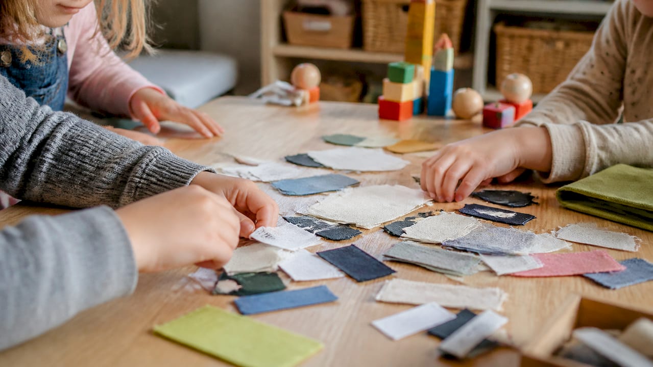 Kinderhände sortieren Etiketten an Kleidungsstücken.