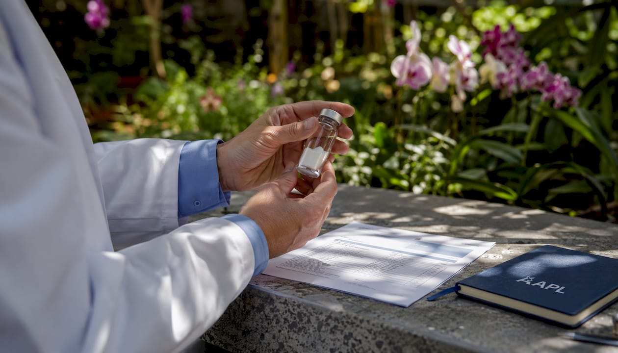 Researcher hands holding Tesamorelin vial and documents
