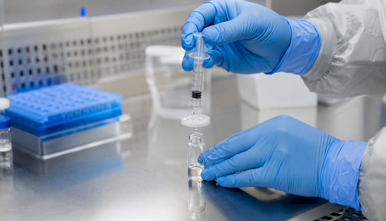 Hands filtering peptide solution with syringe filter
