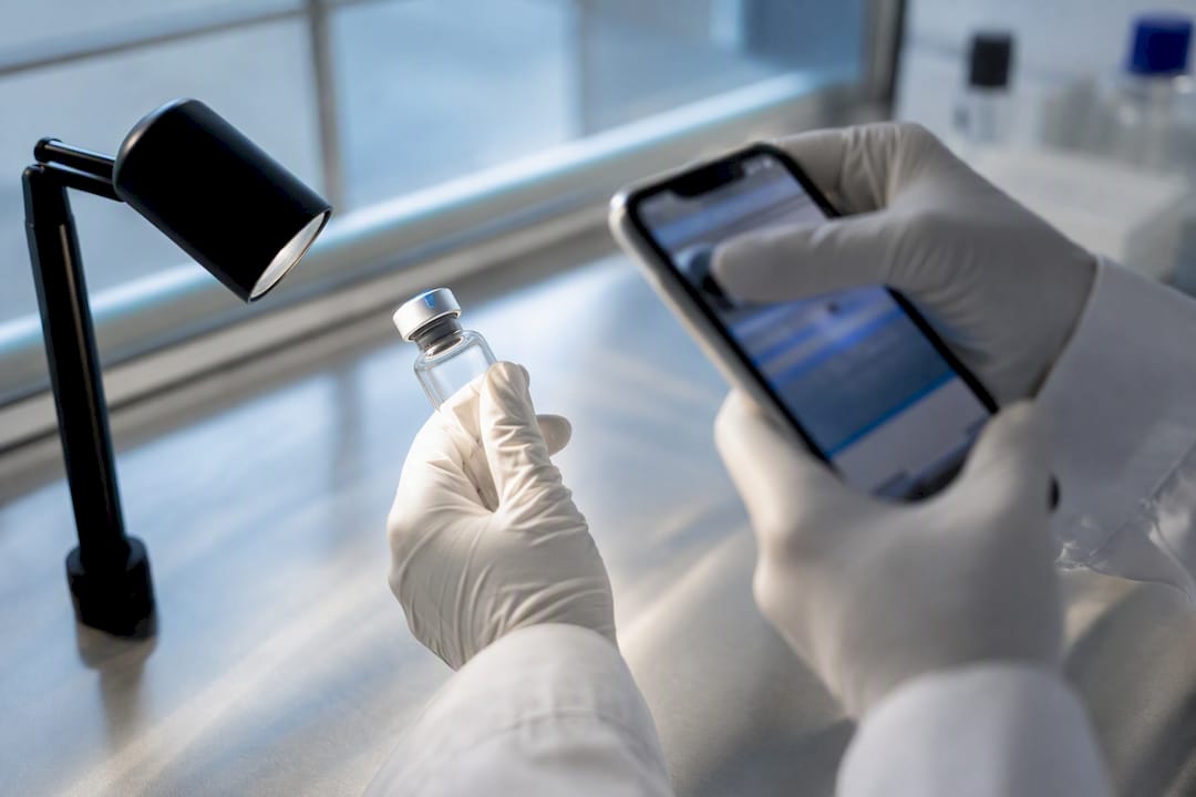 Gloved hands photograph a vial stopper