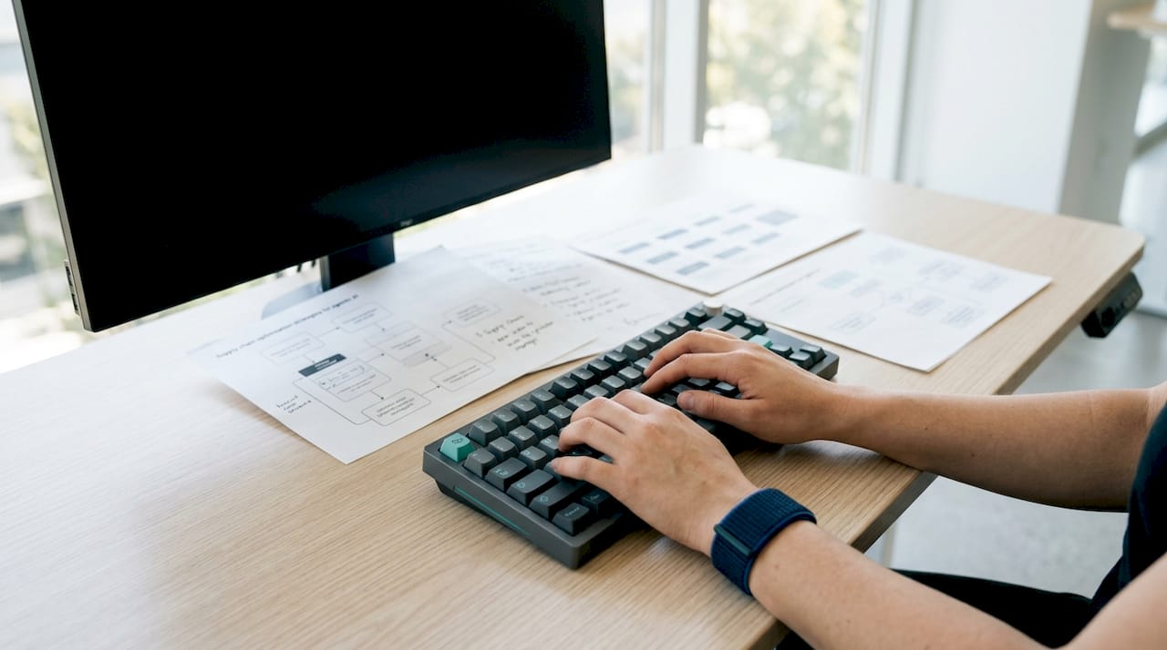 Hands typing code for AI agent orchestration in supply chain
