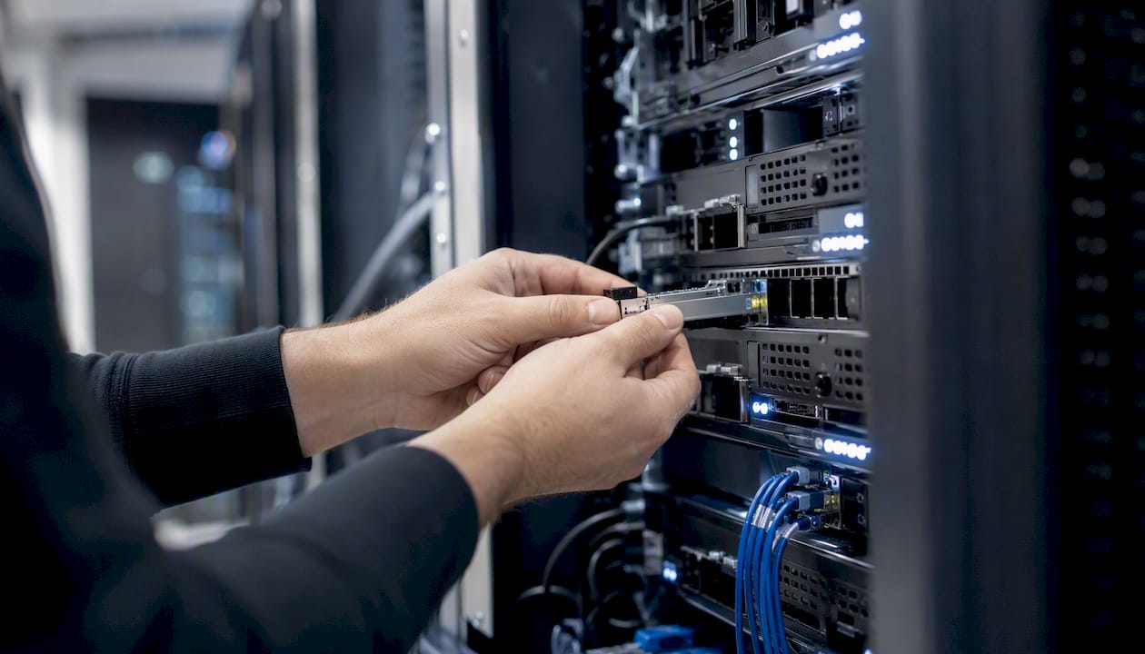 Des mains installent un adaptateur réseau dans un serveur, assurant la connexion et la performance du système.
