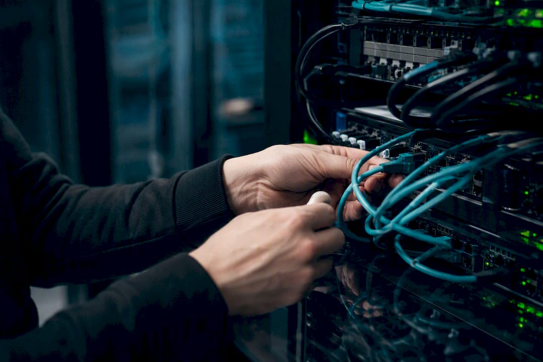 Mains acheminant des câbles réseau vers un panneau de brassage