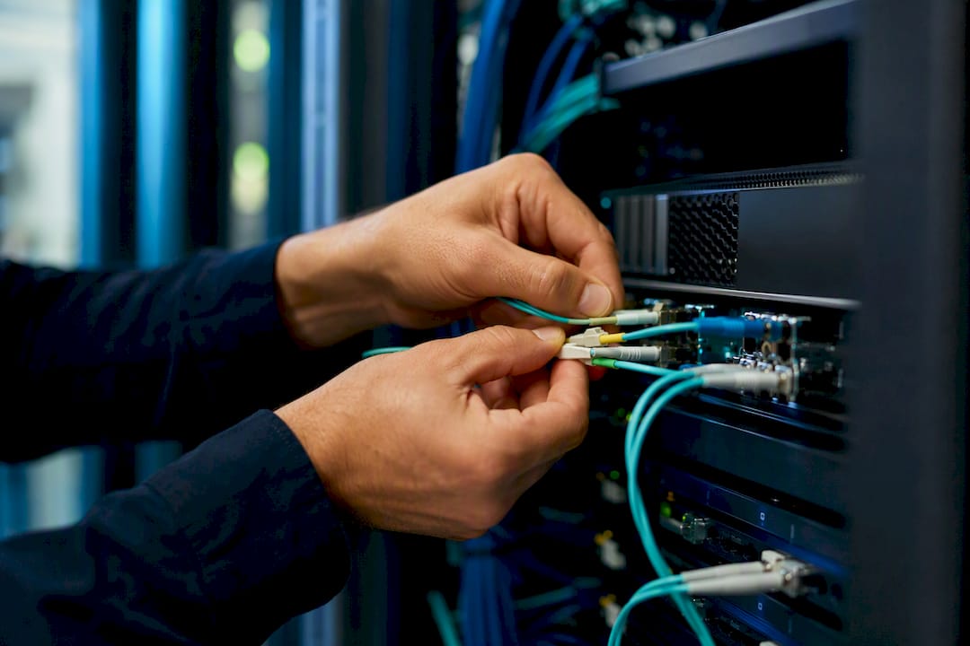 Mains d’un technicien branchant des câbles
