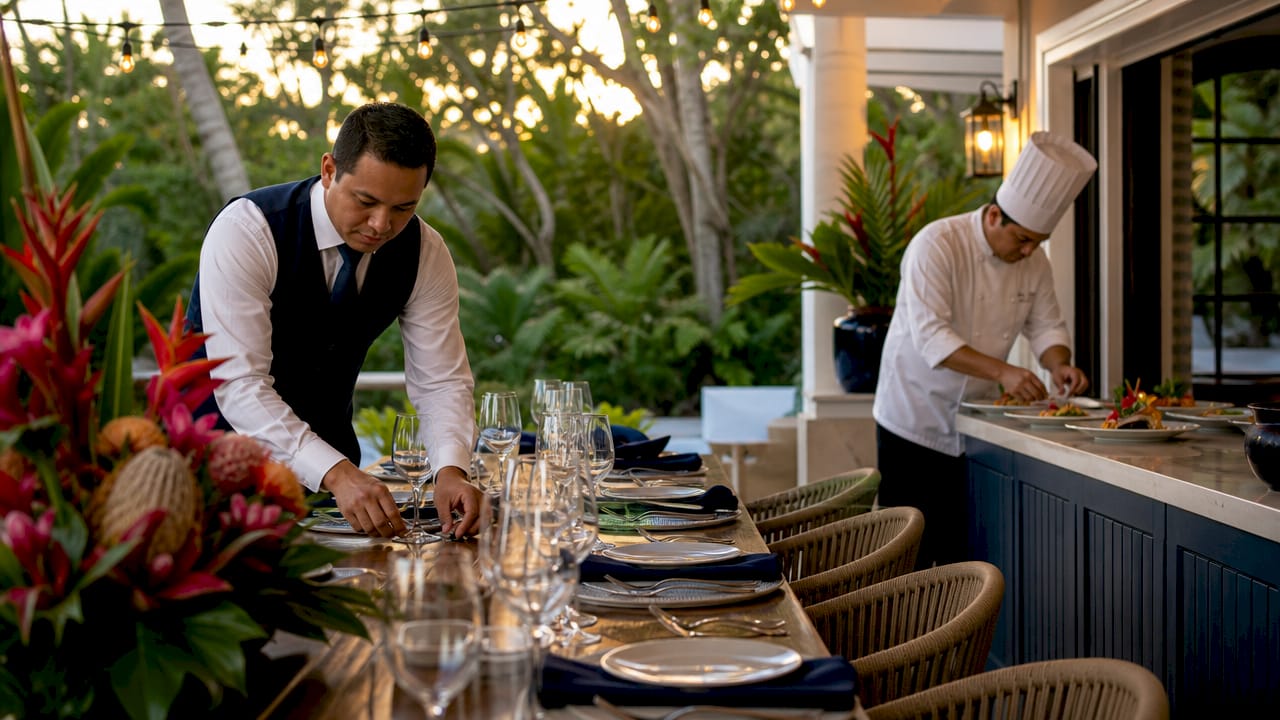 Butler and chef prepare dining table in estate