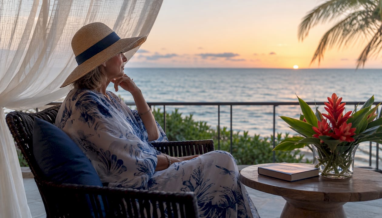 Woman planning beach vacation on balcony overlooking ocean
