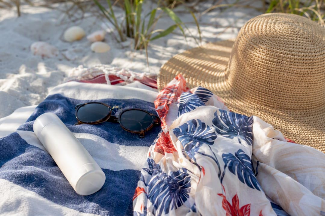 Reef-safe sunscreen and cover-up on beach towel