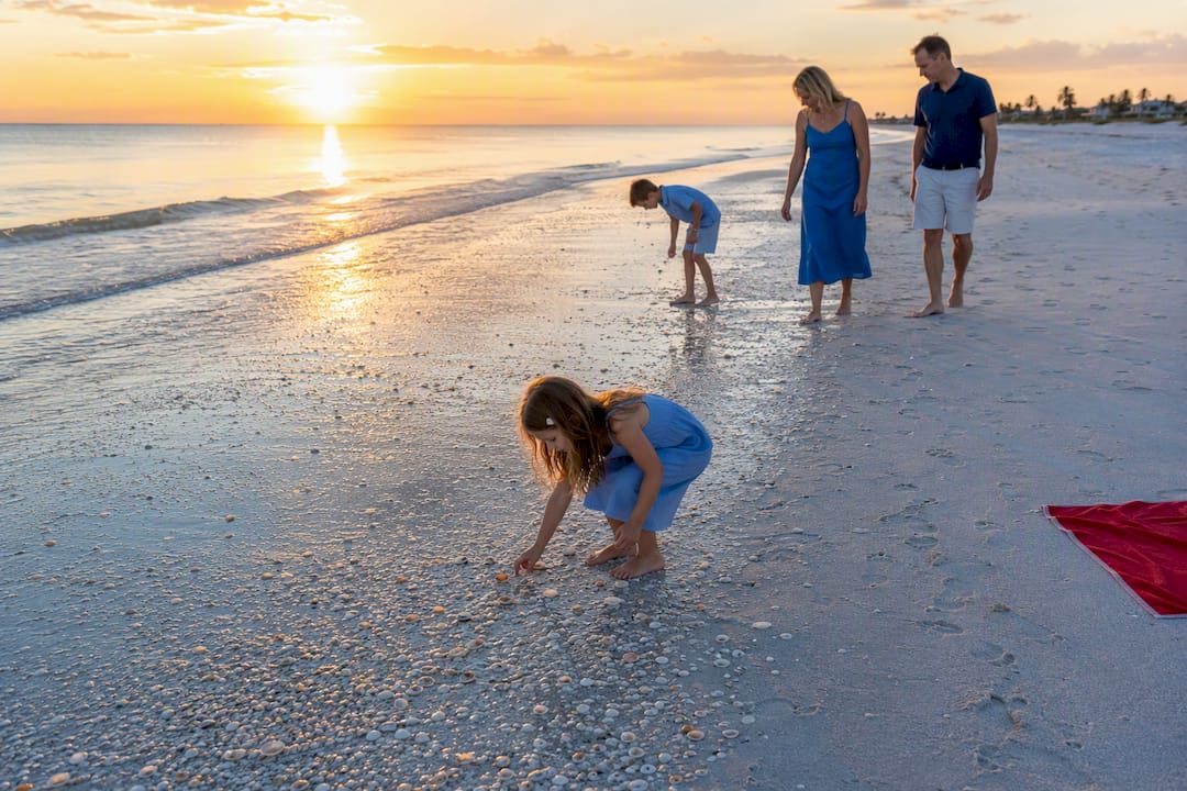 Family shelling along Captiva beach at sunrise