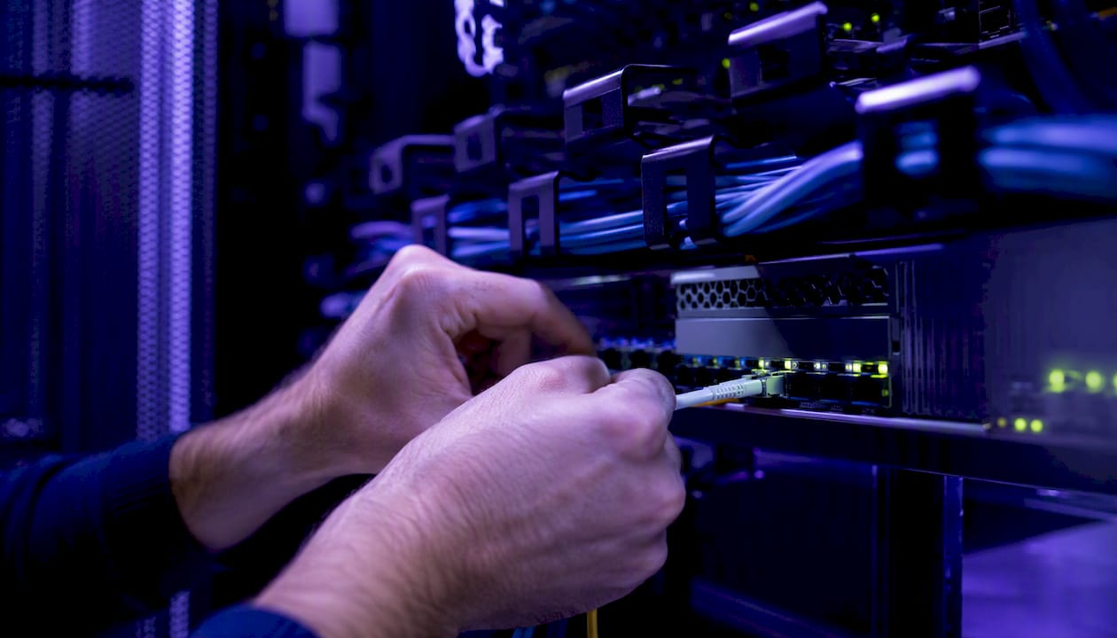 Hands connecting network cable in server rack