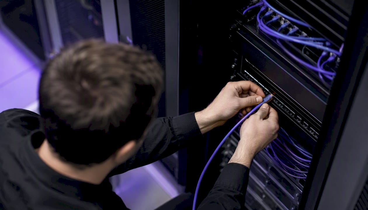 Hands connecting network cable in server room
