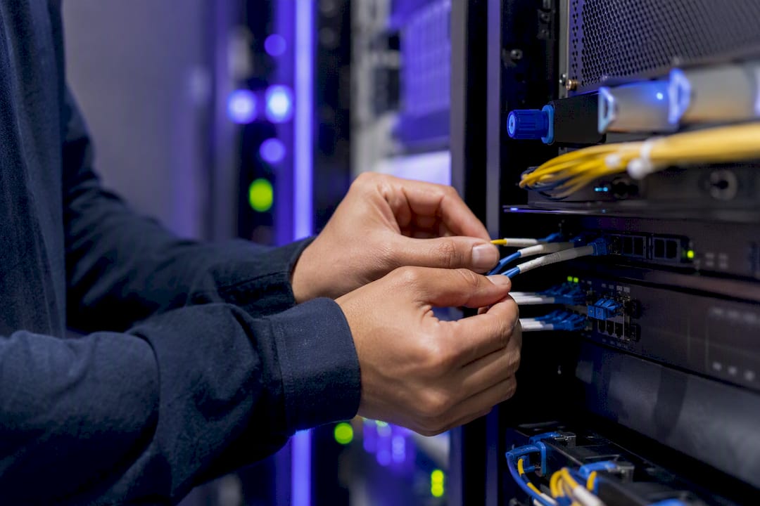 Hands connecting network fiber cables in data center