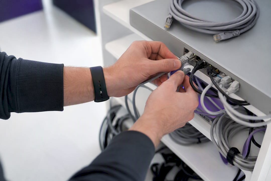 Hands adjusting network patch cable in tech room