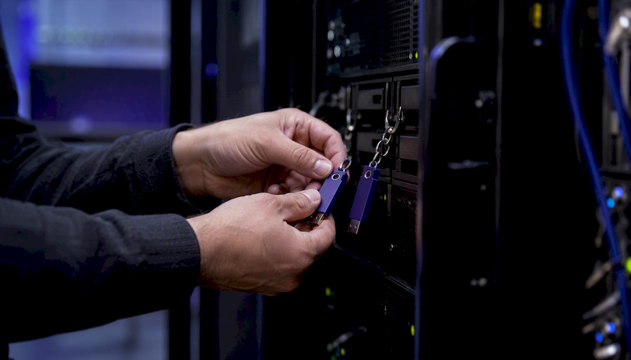 Hands securing encrypted key tokens on server rack