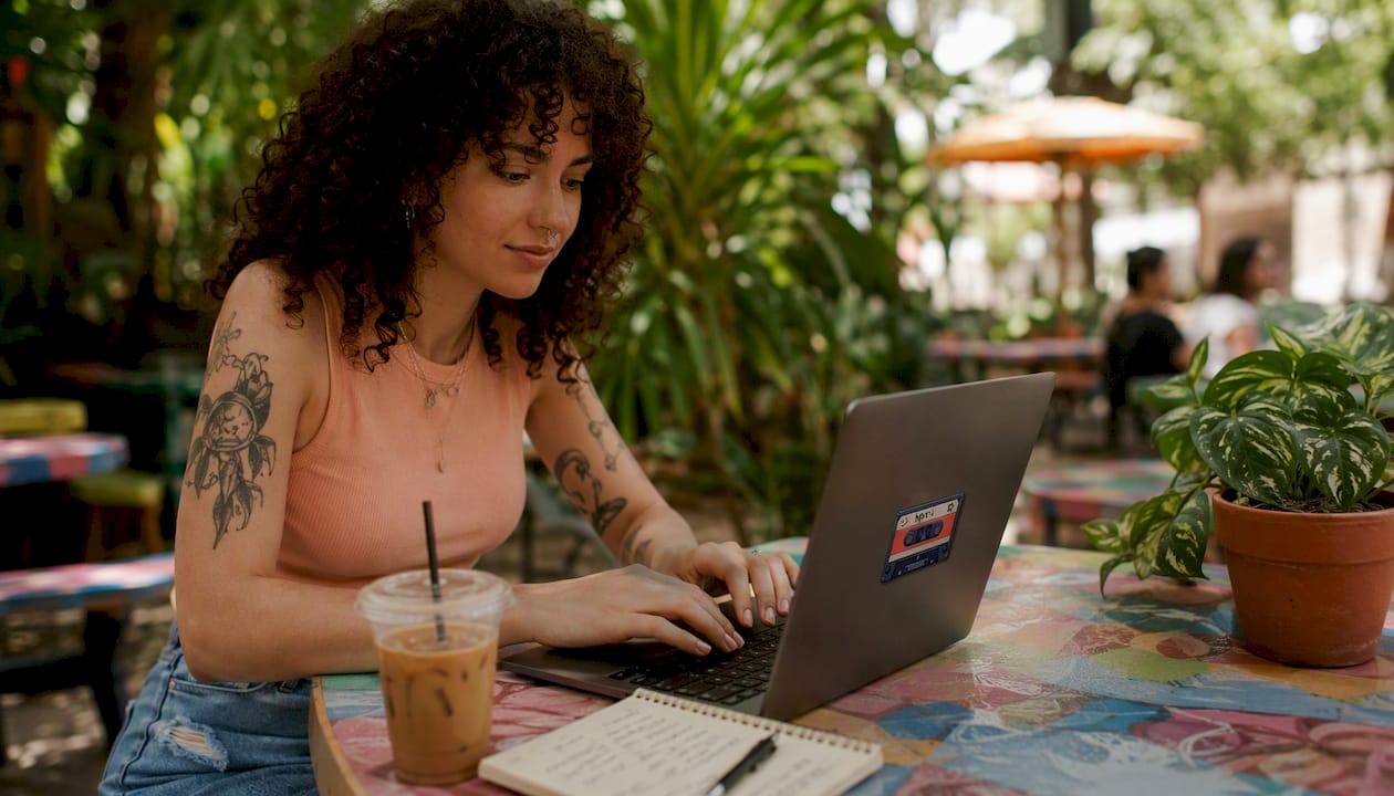 Hands typing on laptop tagging micro-genres at café