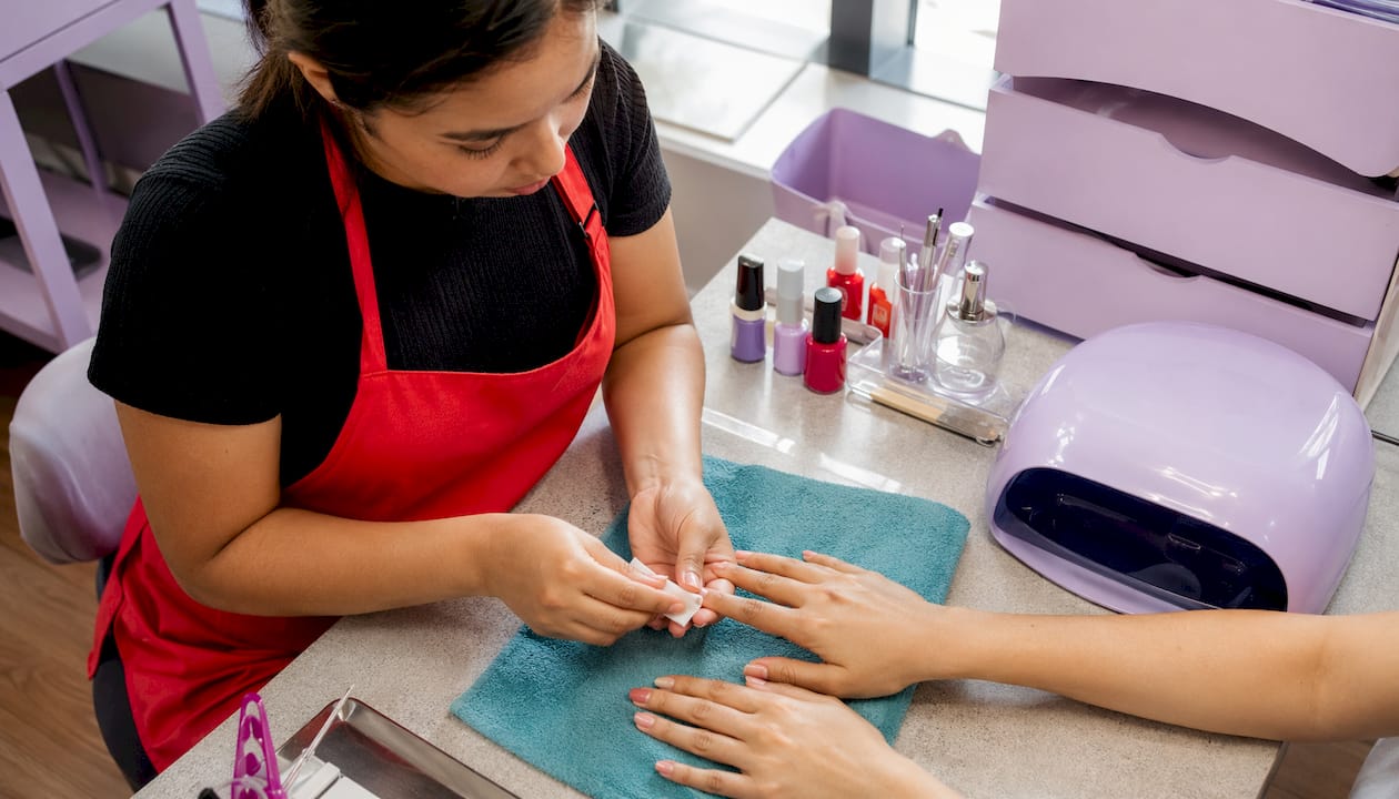 Nail technician prepping nails for gel manicure