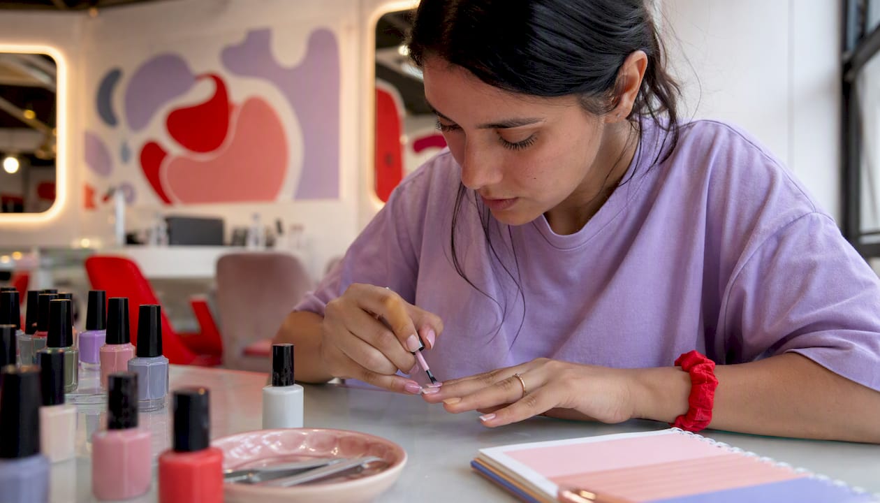 Woman applying glossy nail polish at home table