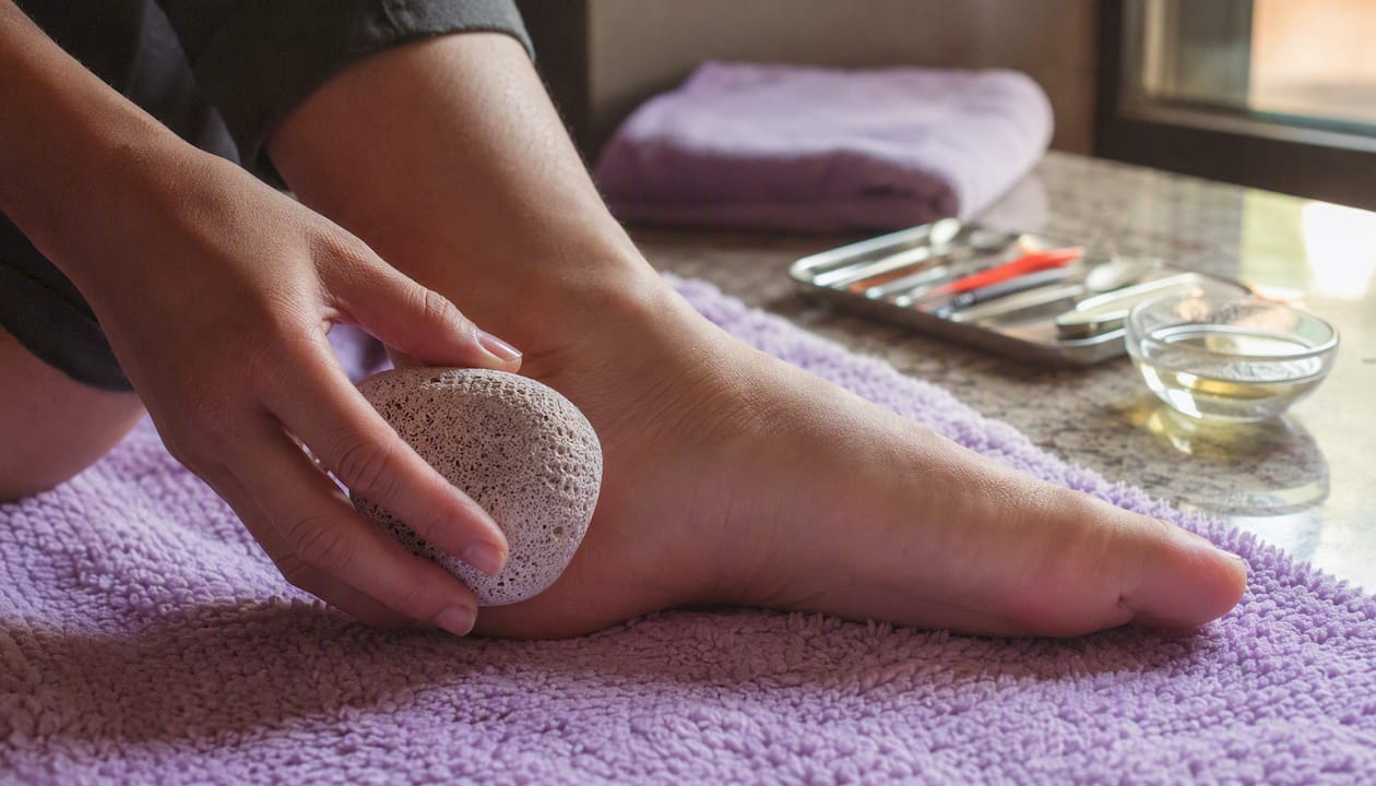 Hand exfoliating foot with pumice stone gently