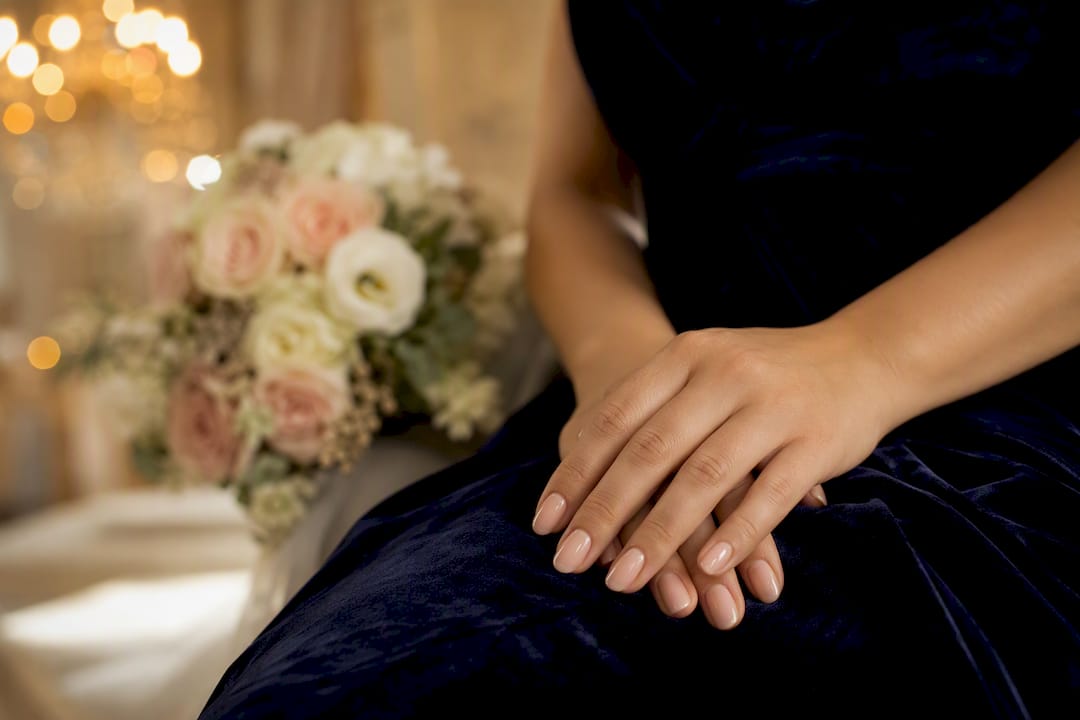 Bridal hands with sheer nude manicure on lace dress