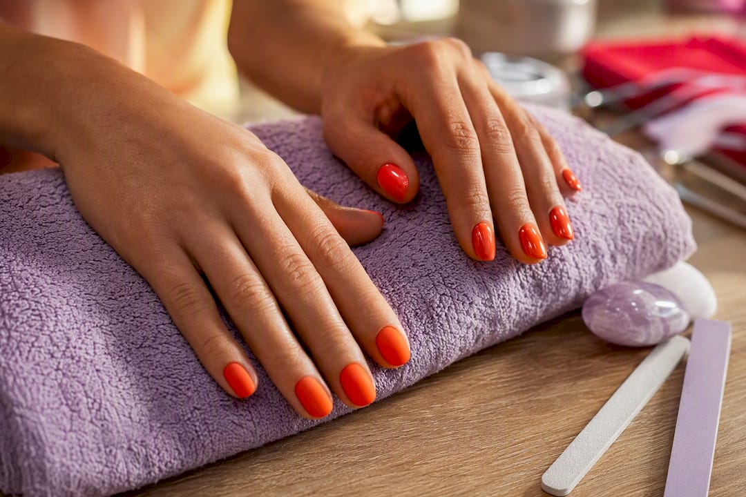 Two hands showing matte and glossy tangerine nails