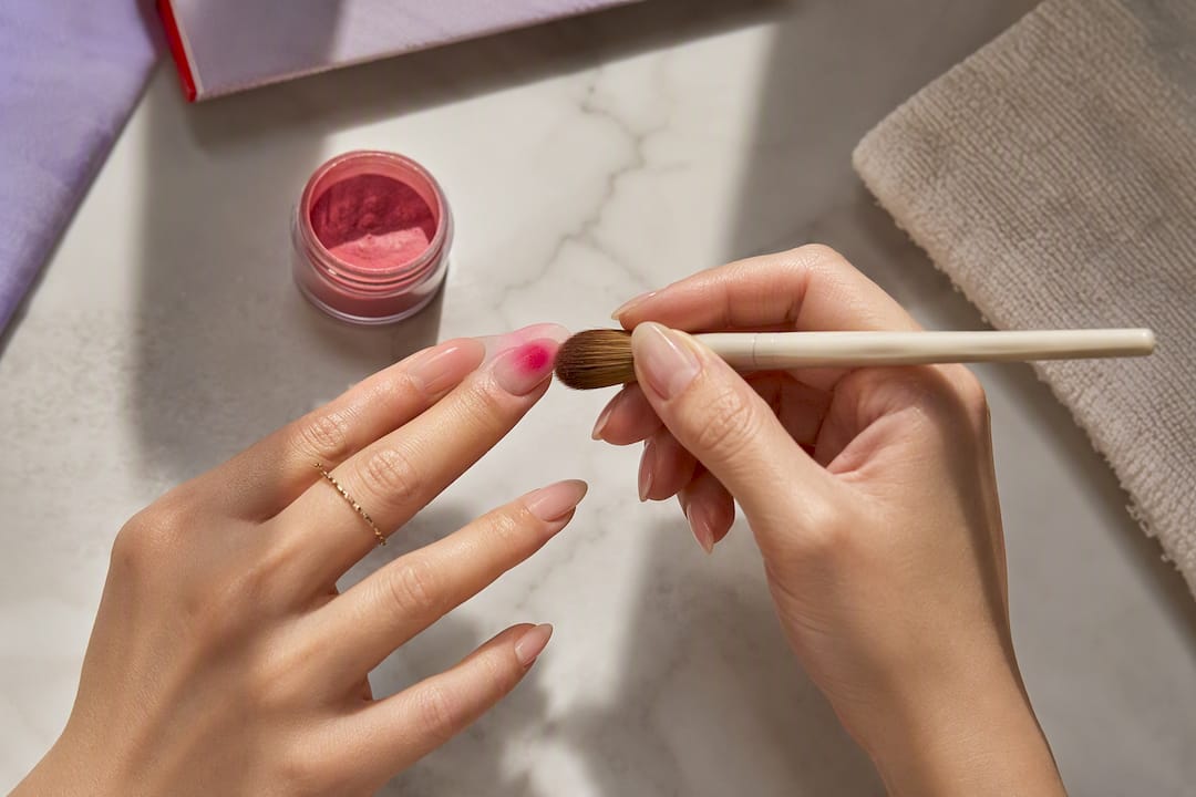 Brush pressing pigment into aura nail center