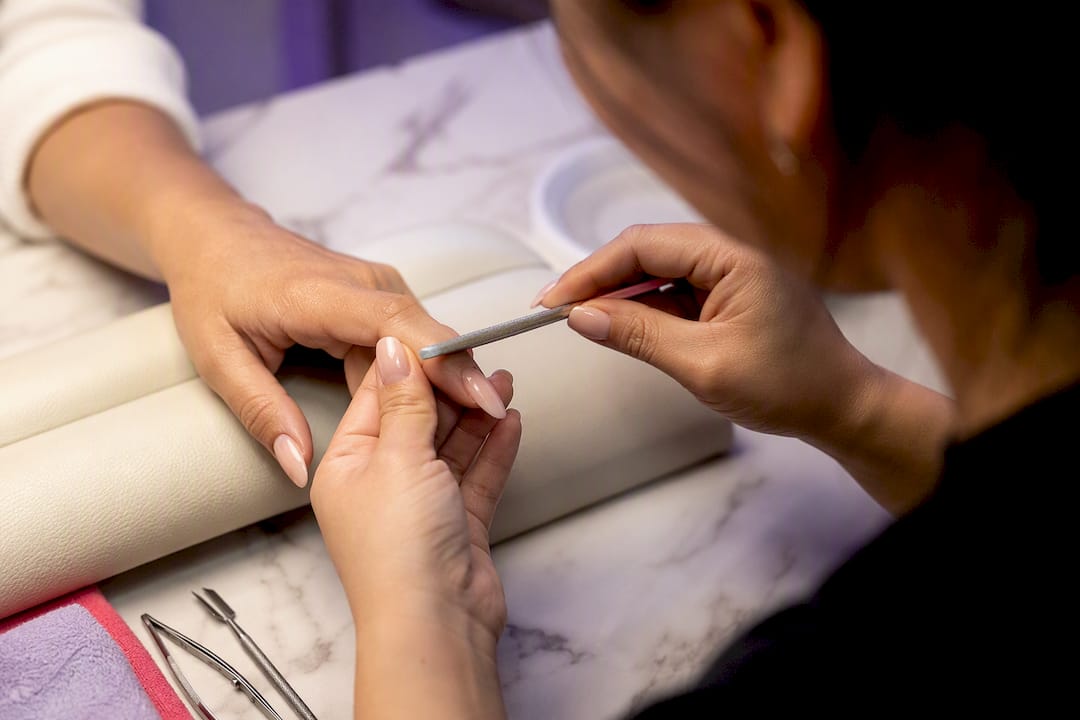 Technician filing acrylic nail with controlled strokes