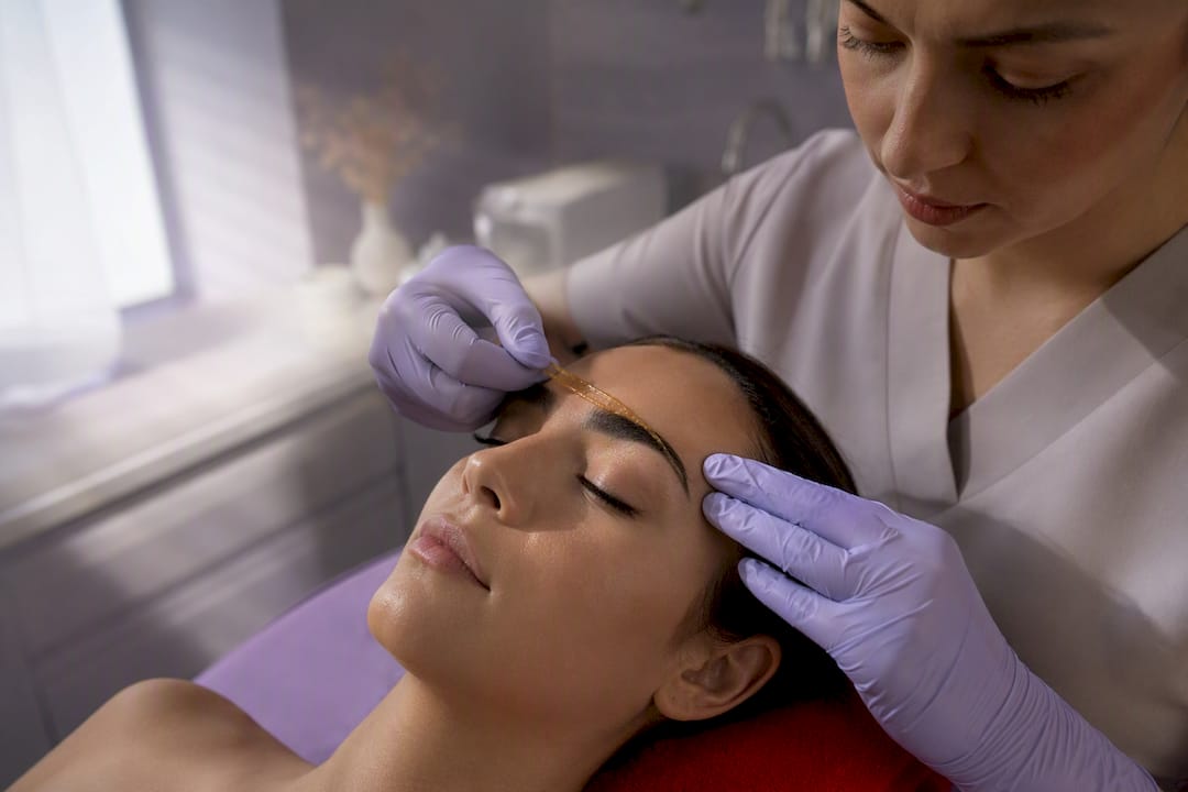 Technician applying facial wax near eyebrow