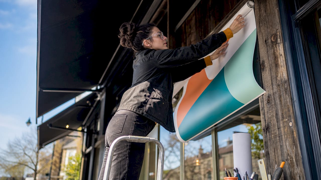 Installer fitting vinyl banner on store exterior