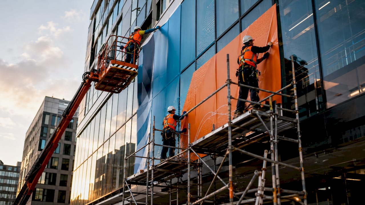 Workers installing large building wrap outdoors