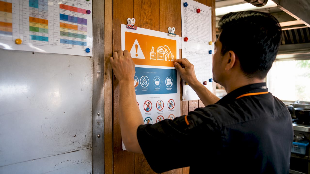 Hands pinning safety poster in workshop