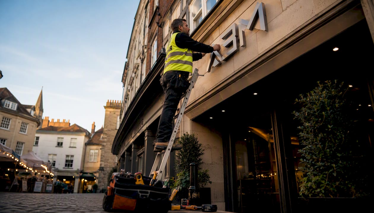 Technician installing corporate entrance sign outdoors