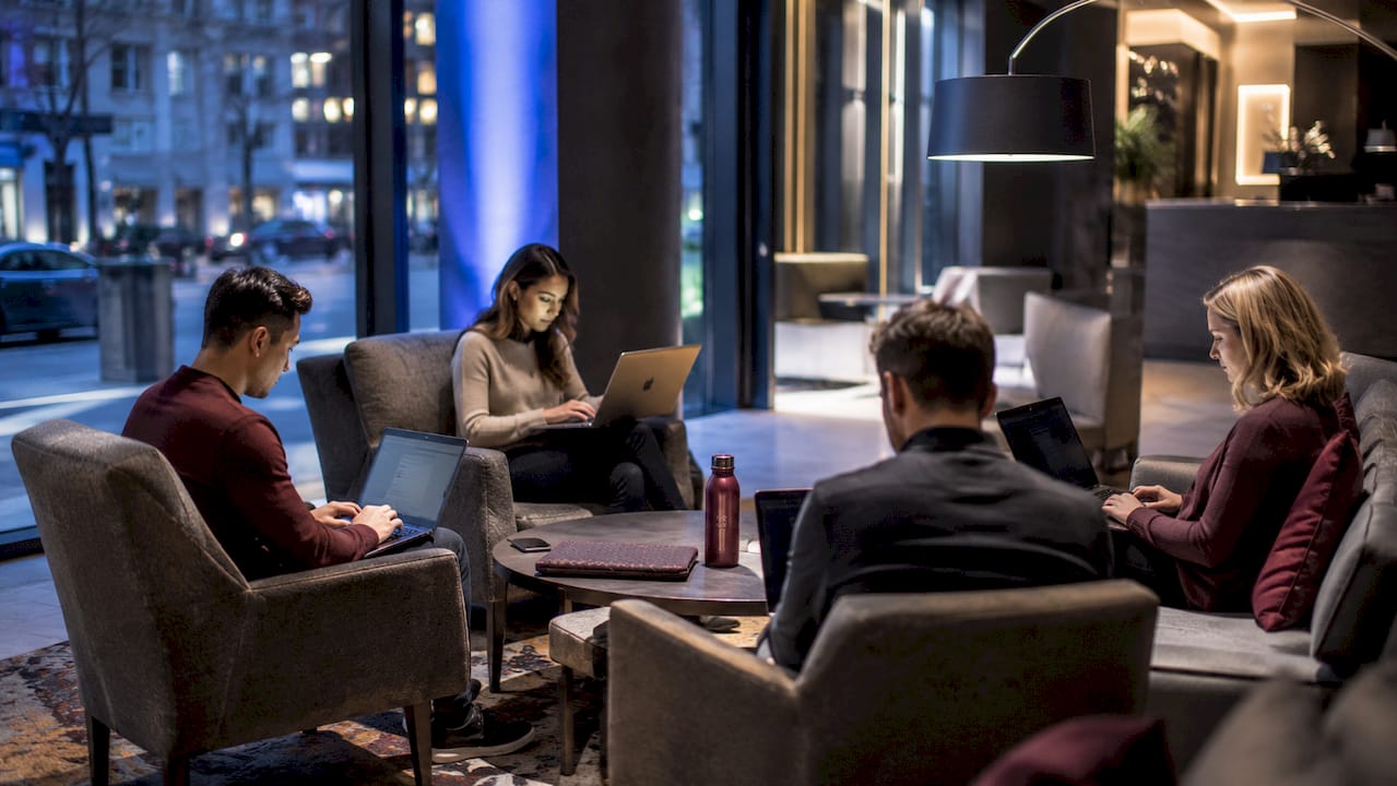 Clustered hotel lobby seating with visible laptop screens