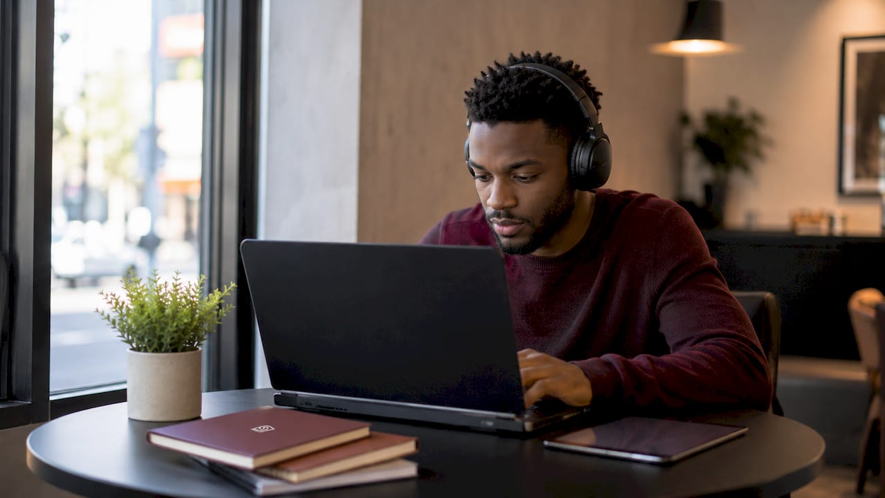 Hombre concentrado ajustando la pantalla de privacidad del portátil en un espacio de coworking