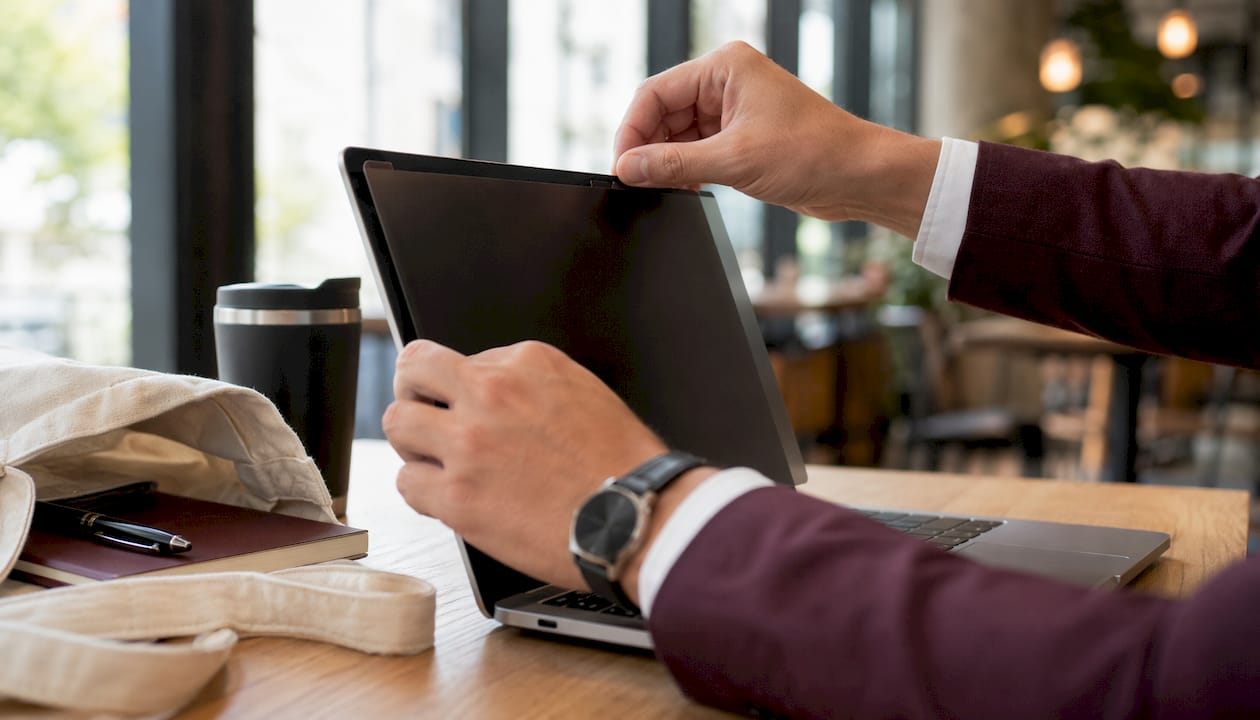 Hands attaching privacy screen to laptop