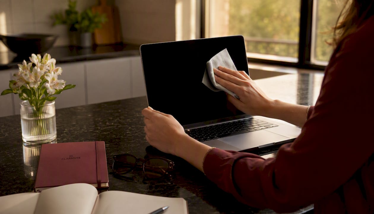 Person cleaning MacBook privacy screen with microfiber cloth