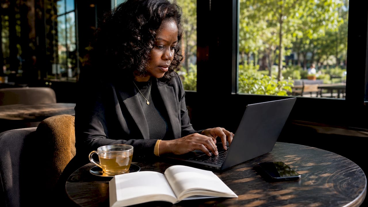 Woman typing pillar page content in café