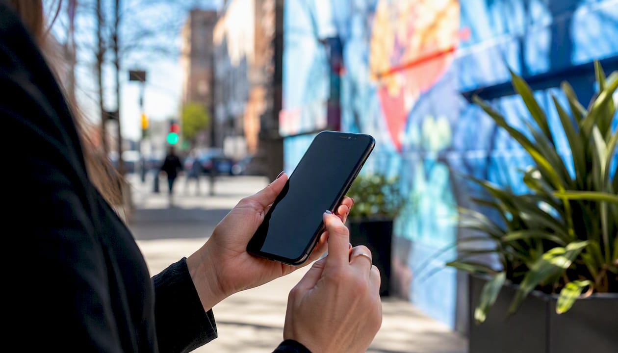 Hand holding phone near local storefront