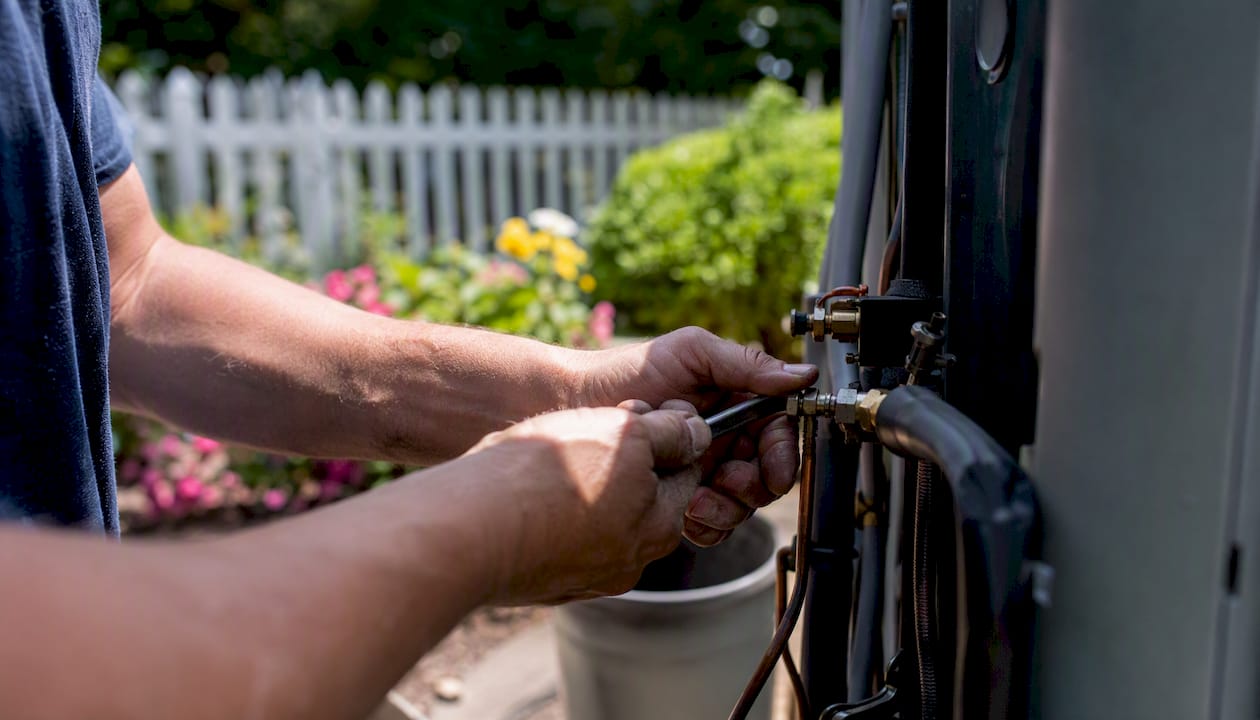 Hands disconnecting AC condenser for replacement