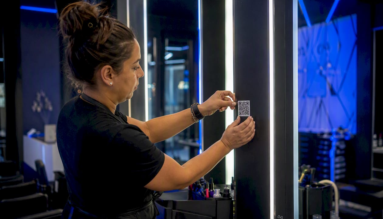 Staff applying QR code sticker on salon mirror