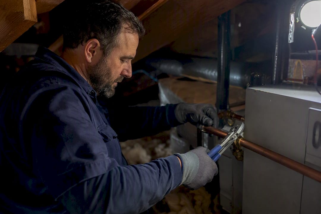 HVAC technician adjusting pipes in basement