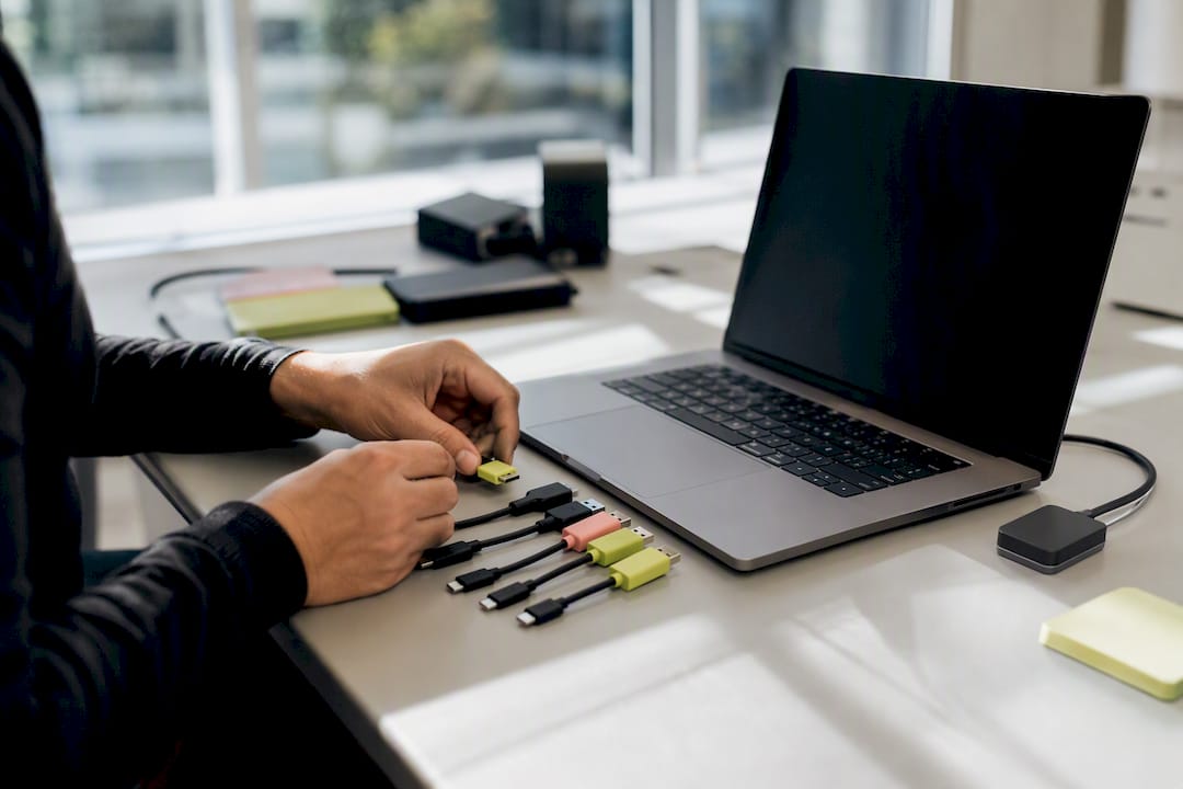 Hands connecting cables in tech workspace