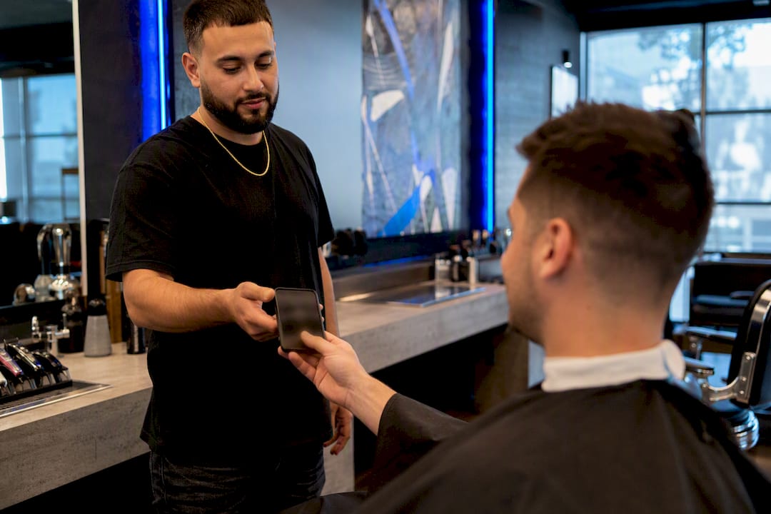 Barber handing client smartphone with app