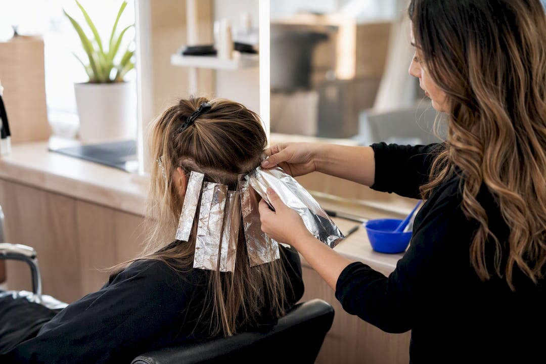 Stylist applying foil highlights in hair